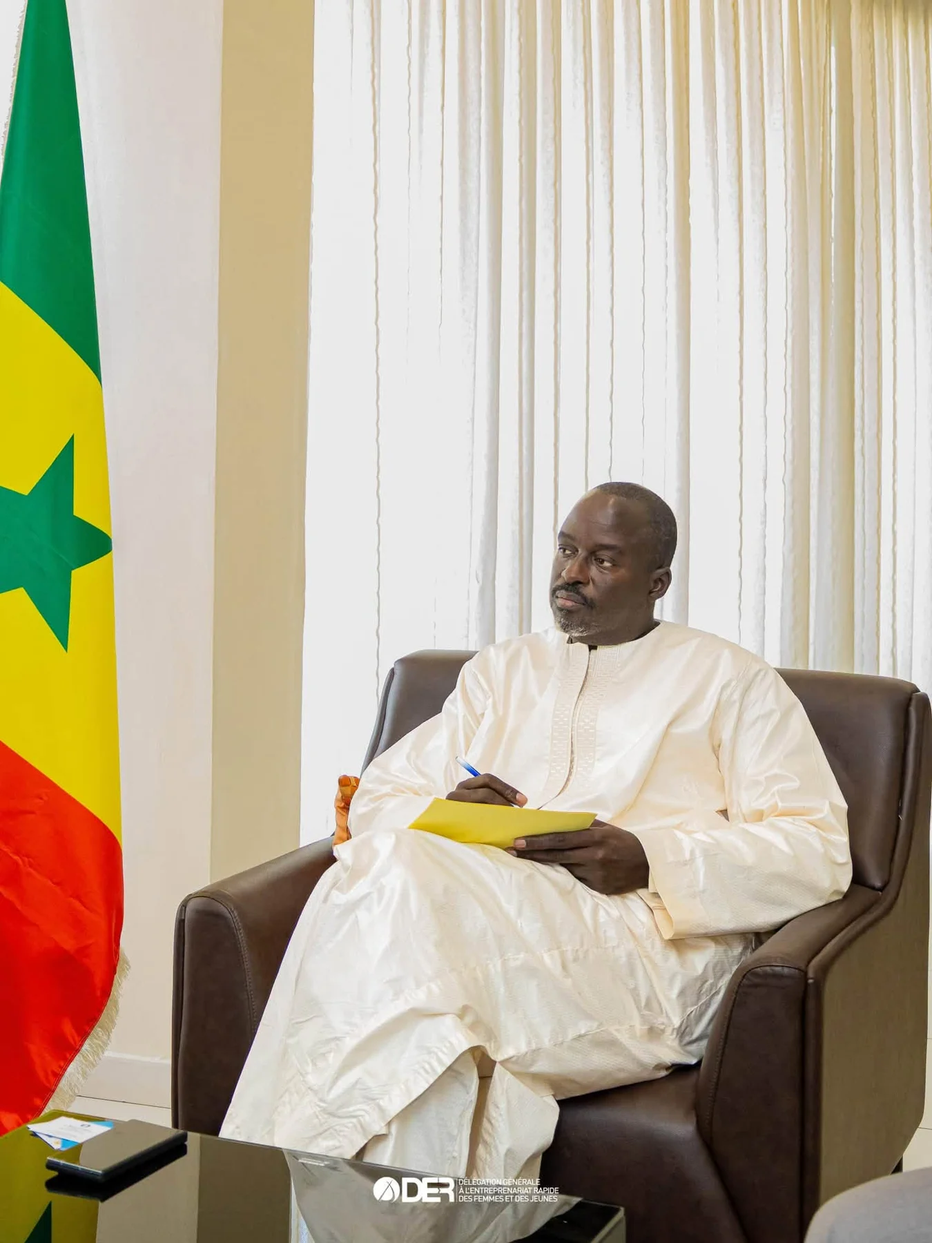 Abdoulaye Niane en tenue blanche, près du drapeau sénégalais